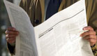 חדשות - איש בז'אקט מחזיק עיתון פתוח בשפה זרה